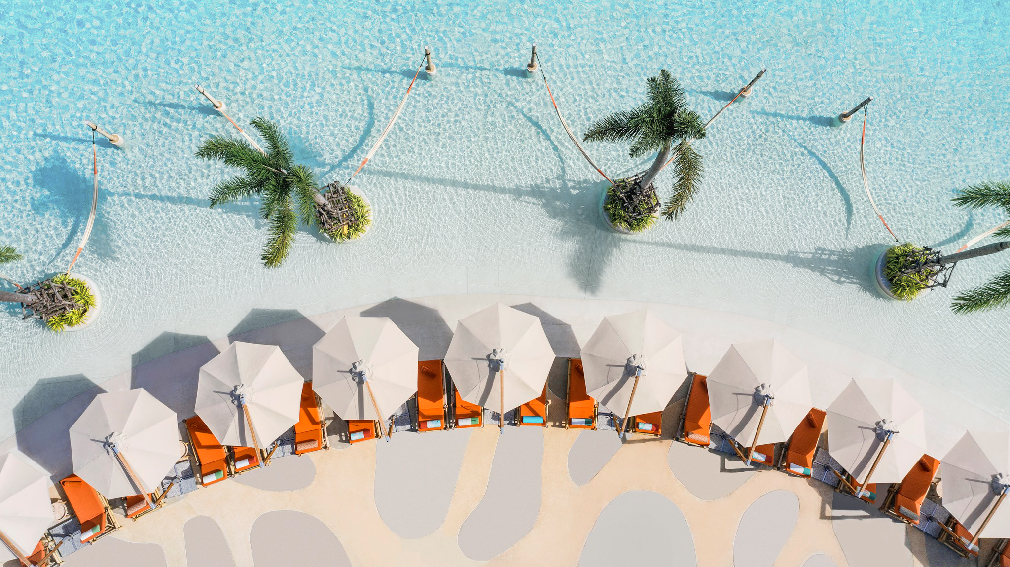 Aerial view of a crystalline lagoon by Crystal Lagoons with orange loungers and two palm trees