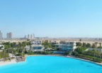 A turquoise lagoon surrounded by luxurious villas in the desert and skyscrapers in the background